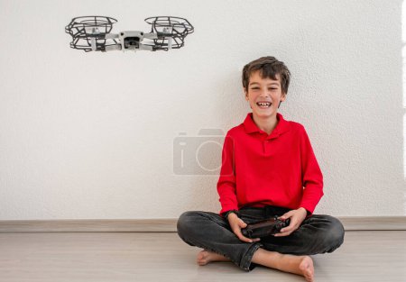 Téléchargez les photos : Cute boy operating the dron or quadcopter by remote control on white background. - en image libre de droit