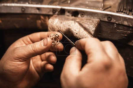 Primer plano de una mano orfebre haciendo un anillo de oro o plata o un diamante usando herramientas orfebres. Hacer anillo con diamantes