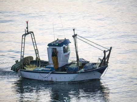 Photo for Fishing boat at dawn off the beach in Fuengirola Spain.These boats came every morning of our stay on the Costa del Sol. I think they were fishing for sardines or anchovies close to the beach - Royalty Free Image