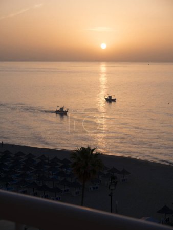 Photo for Fishing boat at dawn off the beach in Fuengirola Spain.These boats came every morning of our stay on the Costa del Sol. I think they were fishing for sardines or anchovies close to the beach - Royalty Free Image