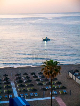 Photo for As dawn breaks over Fuengirola on the Costa del Sol the fishing boats fish close to the beach.However it is still a fishing port with boats arriving with their catches - Royalty Free Image