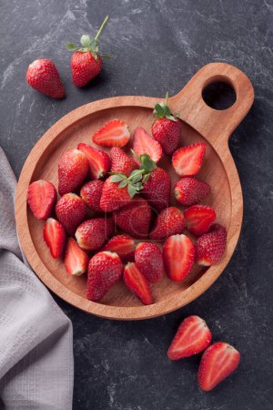Photo for Many strawberries on wooden board with stone texture background - Royalty Free Image