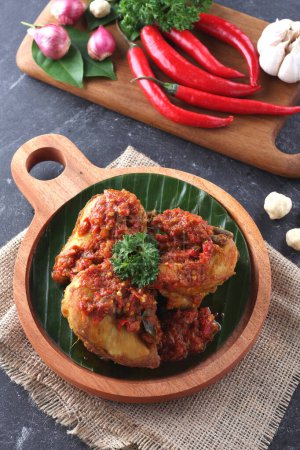 Spicy chicken on wooden board with spices as background