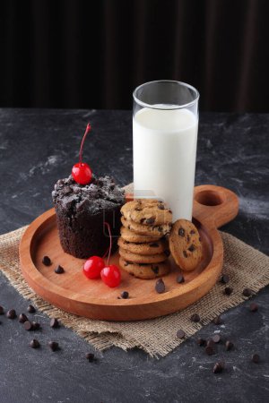 Photo for A glass of milk with chocolate chip cookies and chocolate muffin on wooden plate - Royalty Free Image