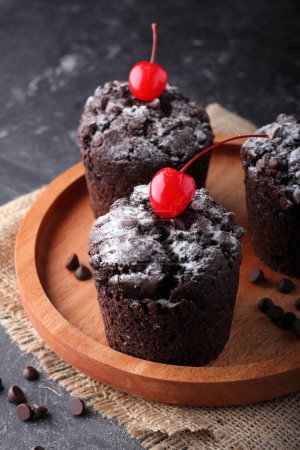 Photo for Chocolate muffin with red cherry on top on wooden board - Royalty Free Image