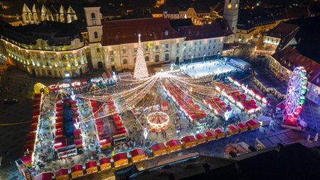 Téléchargez les photos : Photographie de paysage du centre-ville de Sibiu avec la Foire de Noël, prise à partir d'un drone au coucher du soleil avec la foudre de la ville. Vue panoramique sur le paysage urbain de Sibiu, Roumanie. - en image libre de droit