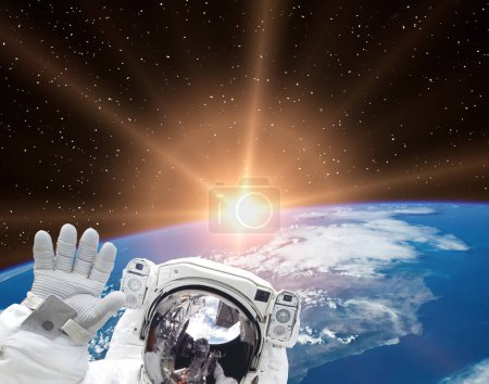 Photo for Astronaut waves against beautiful sunrise. The elements of this image furnished by NASA - Royalty Free Image