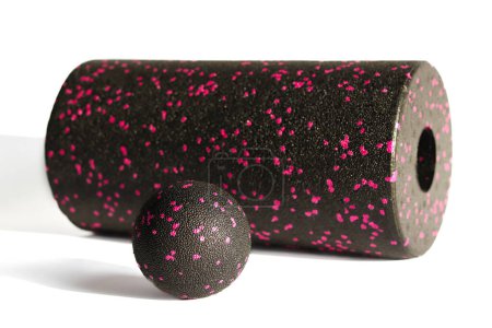 Eine schwarz-rosa Massagerolle und ein Ball für Triggerpunkte isoliert auf weißem Hintergrund. Nahaufnahme. Schaumstoffrollen ist eine selbstmyofasziale Auslösetechnik. Konzept der Fitnessgeräte.