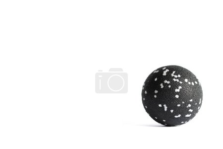 Massage black ball with white spots for trigger points isolated on a white background. Concept of myofascial release.