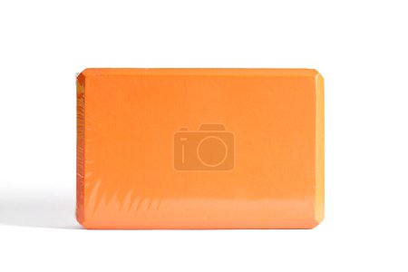 Ein orangefarbener Schaumstoff-Yoga-Block isoliert auf weißem Hintergrund. Konzept der Fitnessgeräte.