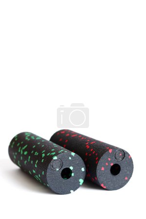 A black green and red massage foam rollers mini isolated on a white background. Close-up. Foam rolling is a self myofascial release technique. Concept of fitness equipment.