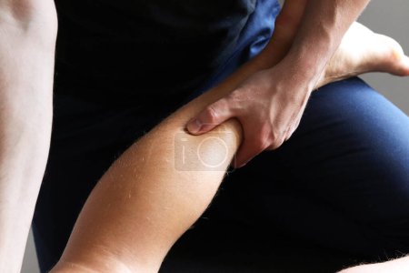 Photo for Masseur does sports legs massage in spa center. Massage of myofascial trigger points on leg of male client to release tension. Rehabilitation, sport therapy medicine. - Royalty Free Image