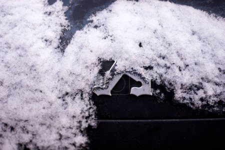 Téléchargez les photos : Mulhouse - France - 19 janvier 2024 - Gros plan du logo Peugeot recouvert de neige sur une voiture grise garée dans la rue - en image libre de droit