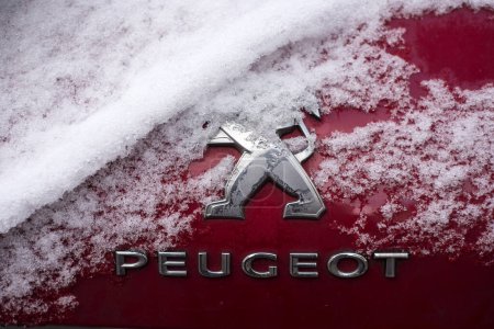 Téléchargez les photos : Mulhouse - France - 19 janvier 2024 - Gros plan du logo Peugeot recouvert de neige sur une voiture rouge garée dans la rue - en image libre de droit
