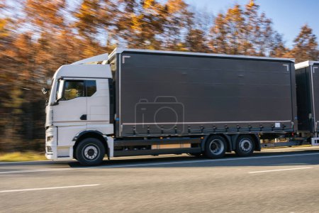 Photo for Truck is driving through the forest in autumn. Car transport . T - Royalty Free Image