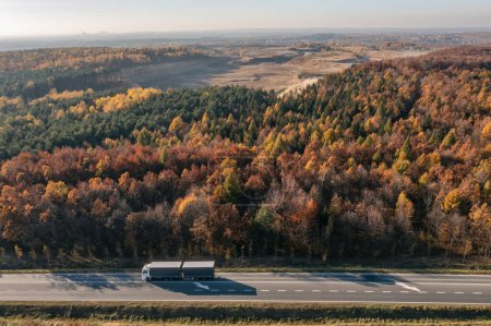 Téléchargez les photos : Camion conduit à travers la forêt en automne. Transport en voiture. T - en image libre de droit