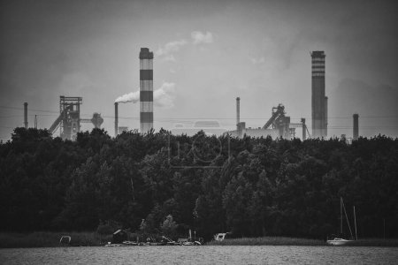 Photo for Industrial steel factory, iron works. Metallurgical plant. steelworks. Heavy industry in Europe. Air pollution from chimneys. Ironworks on a background of blue lake.  Nature and industry. - Royalty Free Image