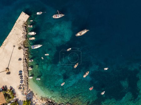 Foto de Foto aérea de aviones no tripulados de Agios Nikolaos - un pequeño puerto en la isla de Zante. Puerto en una isla griega con agua azul turquesa con muchos barcos y yates en el agua en Grecia, Zakynthos. - Imagen libre de derechos