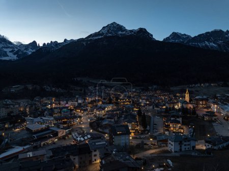Aerial drone view of Andalo town at night  with mountains background in winter. Ski resort Paganella Andalo, Trentino-Alto Adige, Italy., Italian Dolomites,.Pagnella valley. Snow covered Italian Dolomites at winter. 