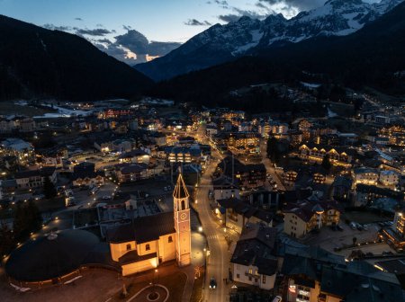 Drohnenaufnahme der Stadt Andalo bei Nacht mit dem Hintergrund der Berge im Winter. Skigebiet Paganella Andalo, Trentino-Südtirol, Italien., Italienische Dolomiten, Pagnella-Tal. Schneebedeckte italienische Dolomiten im Winter. 