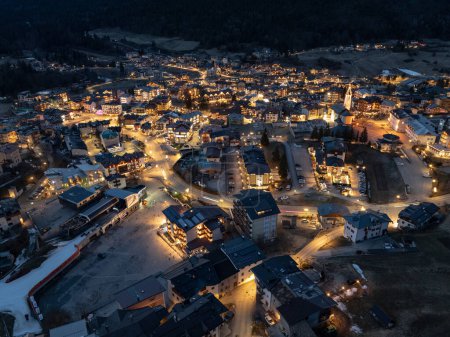 Drohnenaufnahme der Stadt Andalo bei Nacht mit dem Hintergrund der Berge im Winter. Skigebiet Paganella Andalo, Trentino-Südtirol, Italien., Italienische Dolomiten, Pagnella-Tal. Schneebedeckte italienische Dolomiten im Winter. 