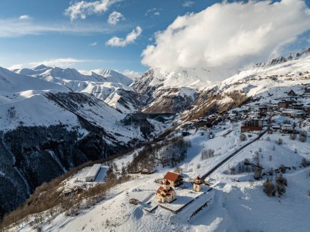 Vista aérea del dron de la colina superior de la iglesia de Amaglebis eklesia en Gudauri, Georgia. Arquitectura ortodoxa en el Cáucaso. Estación de esquí de Gudauri en invierno. Montañas del Cáucaso en Georgia