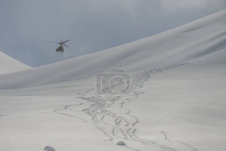 Helicopter in the mountains. freeride heliboarding in the Caucasus. Freeride snowboarding in winter. Heliboarding freeride. Riding in powder on snowborad. Freeride in Caucasus mountains. 