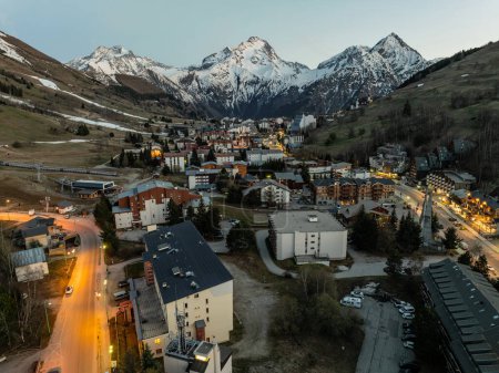 Aerial drone photo Blue Hour French alps in winter, Rhone Alpes in France Europe. Les deux alpes village in spring time. Town in the alps mountains during sunset. Winter French Alpes town from drone