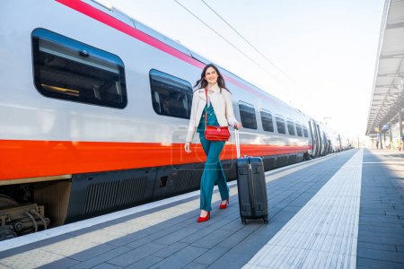 Portrait d'une femme d'affaires qui se promène dans une gare ou un aéroport pour se rendre à la porte d'embarquement avec bagages à main