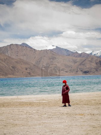 Photo for Ladakh, India - June 18, 2022 : Little buddhist monk wearing Covid mask near beautiful Pangong lake. - Royalty Free Image