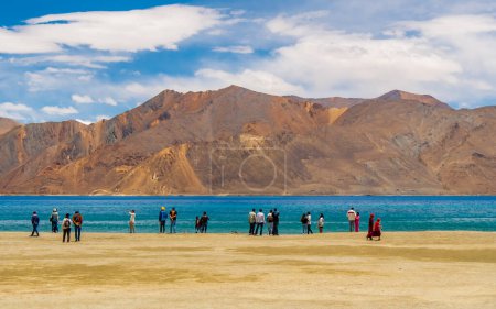 Photo for Ladakh, India - June 26, 2022 : Unidentifed Red SUV or car at Pangong Lake worlds highest saltwater lake dyed in blue stand in stark contrast to the arid mountains surrounding it. - Royalty Free Image