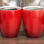 Red porcelain coffee cups with heart shaped steam. 3D illustration.