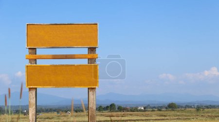 Téléchargez les photos : Vieux panneau en bois avec les jambes sur le terrain et les montagnes en arrière-plan, espace de copie - en image libre de droit