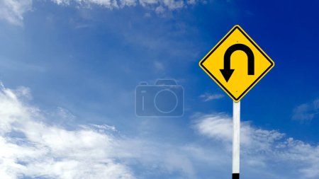 Téléchargez les photos : Panneau d'avertissement jaune avec flèche de virage u gauche sur fond bleu ciel - en image libre de droit