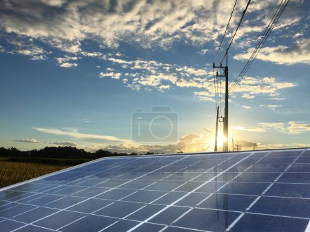 Téléchargez les photos : Panneau photovoltaïque avec le poteau d'alimentation et le ciel bleu dans la lumière du soleil du soir sombre en arrière-plan - en image libre de droit