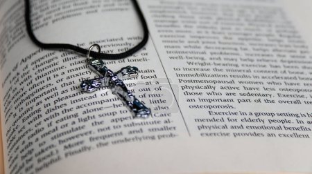 Téléchargez les photos : Croix en métal brillant sur vieux livre pour rappeler la bonté de Jésus-Christ pour tous les chrétiens - en image libre de droit