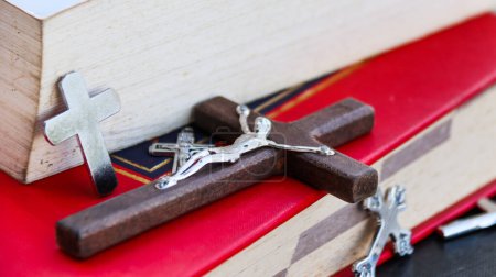 Téléchargez les photos : Fermer croix en bois brun foncé sur vieux livres avec fond flou - en image libre de droit