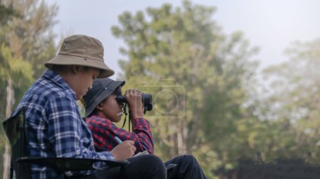 Foto de Niños asiáticos jóvenes están usando un binocular para buscar aves y animales en un parque local, enfoque suave y selectivo - Imagen libre de derechos