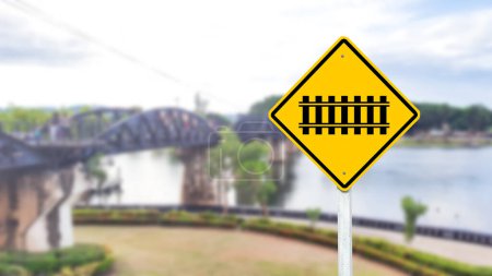 Un symbole de passage à niveau noir est bien en évidence sur un panneau jaune vif. Ce panneau avertit les conducteurs et les piétons de la présence d'un passage à niveau. promouvoir la sécurité et la prudence dans les environs.