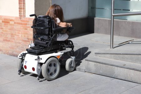 Foto de Una joven discapacitada en silla de ruedas con movilidad reducida encuentra un obstáculo para acceder a una rampa para sillas de ruedas. - Imagen libre de derechos