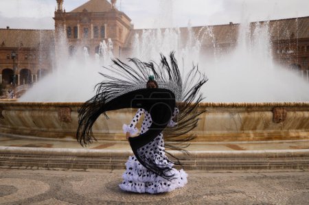 Foto de Bailarina flamenca, morena adolescente y hermosa bailarina típica española baila con un chal negro frente a una fuente en una plaza de Sevilla. Concepto flamenco del patrimonio cultural mundial. - Imagen libre de derechos