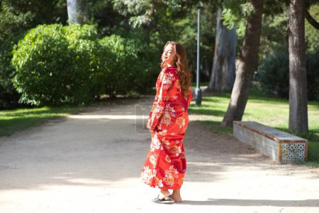 Téléchargez les photos : Une belle femme porte une robe traditionnelle marocaine en rouge et brodée d'or et d'argent. La fille pose pour les photos de mariage dans un jardin de style marocain avec fontaines et verdure luxuriante. - en image libre de droit