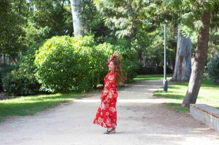 Téléchargez les photos : Une belle femme porte une robe traditionnelle marocaine en rouge et brodée d'or et d'argent. La fille pose pour les photos de mariage dans un jardin de style marocain avec fontaines et verdure luxuriante. - en image libre de droit