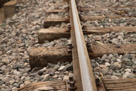 Téléchargez les photos : Détail du rail de la voie ferrée, pierres, vis et traverses en bois. Notion de moyen de transport - en image libre de droit