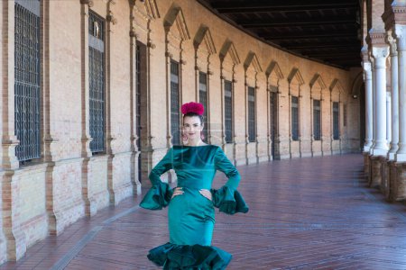 Foto de Mujer joven y hermosa con vestido verde típico con volantes y baile flamenco en plaza de espana en Sevilla, andalusia, paseos con arte y pasión. 16 de noviembre, día internacional del flamenco - Imagen libre de derechos