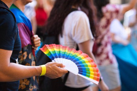 A person with a gay pride fan during the demonstration for the rights of homosexuals and LGBTQ people in the city of Seville, Spain. Concept of equality and gay rights