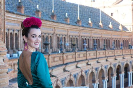 Téléchargez les photos : Belle jeune femme avec robe à volants vert typique et danse flamenco sur la place d'Espagne à sevilla, andalousie, elle est sur un balcon de la célèbre place. 16 novembre, Journée internationale du flamenco - en image libre de droit