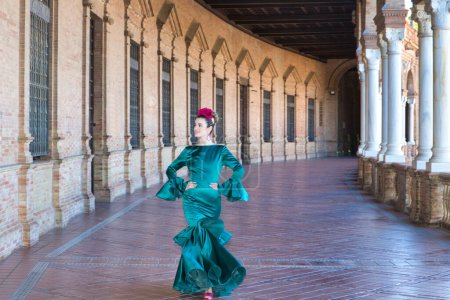 Foto de Mujer joven y hermosa con vestido verde típico con volantes y baile flamenco en plaza de espana en Sevilla, andalusia, paseos con arte y pasión. 16 de noviembre, día internacional del flamenco - Imagen libre de derechos