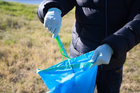 Détail de la main d'un volontaire ramassant des pailles en plastique de la forêt et les mettant dans le sac en plastique. Concept de Journée de la Terre et Journée mondiale de l'environnement 5 juin.