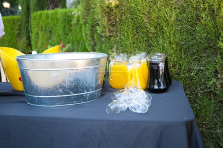 Photo for Pitchers with cola and orange with ice and glasses to serve at an outdoor event. Catering and hospitality service concept - Royalty Free Image